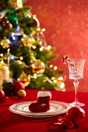 Téléchargez les photos : Une chaussette de Noël en laine est placée sur un plat rond, affichée avec des boules et un verre à vin contenant une canne à sucre. Noël est une fête centrale de l'année chrétienne - en image libre de droit