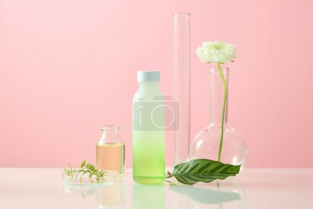 Photo for Laboratory concept with an empty label bottle arranged with a petri dish and other glassware. Research and development cosmetics concept. Pink background - Royalty Free Image