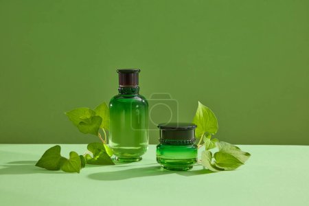 Photo for Empty label bottle and jar decorated over green background with fish mint leaves. Fish mint (Houttuynia cordata) is effectively treats acne and helps skin cells regenerate - Royalty Free Image