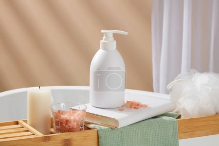 Photo for A book with unbranded pump bottle standing on, displayed with a candle, bowl of pink himalayan salt and a bath sponge. Mockup of skin care cosmetic bottle of beauty facial - Royalty Free Image