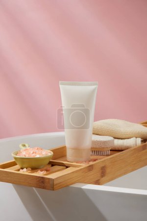 Photo for A dish of pink himalayan salt decorated with empty label tube, foot scrubber brush and a stack of towels. Bathroom view. Container packaging of skin care branding - Royalty Free Image