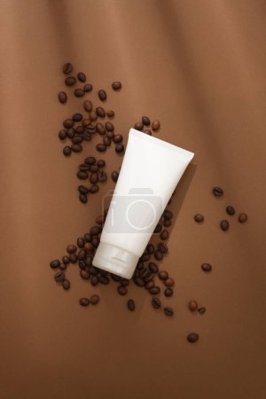 Photo for Against the brown background, white plastic tube container for mask or scrub decorated with coffee beans. Cosmetics tubes mockup for design, organic cosmetics, beauty products concept - Royalty Free Image