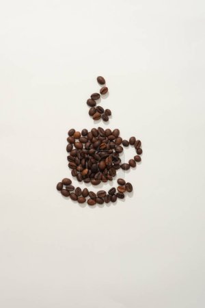 Foto de En el fondo blanco, granos de café tostados marrones dispuestos en forma de una taza de café con humo caliente que sale de ella. Fondo creativo para la publicidad. Vista superior - Imagen libre de derechos