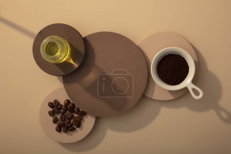 Téléchargez les photos : Vue de dessus des podiums brun foncé et clair décorés sur fond brun avec des grains de café, de la poudre de café et un pot d'huile en verre. Espace vide pour le produit d'affichage - en image libre de droit