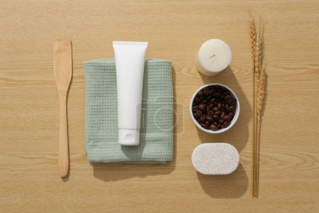Photo for The concept of organic natural cosmetics. A white plastic bottle on green towel, bowl of coffee bean and ear of wheat decorated on wooden background. Top view, space for design - Royalty Free Image