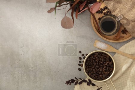 Téléchargez les photos : Le cadre photo est décoré avec des grains de café, des tasses à café, des feuilles colorées et du tissu rugueux sur un fond de ciment. Espace vide pour le texte ou le design. Vue du dessus - en image libre de droit