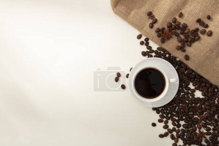 Foto de En el fondo blanco, una taza de café se muestra con granos de café y arpillera marrón. Espacio en blanco para el diseño, producto de presentación con ingrediente del café. Vista superior - Imagen libre de derechos