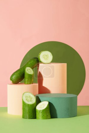 Photo for Three podiums in coral and green color decorated with halves of cucumber. Concept scene stage showcase for new product, promotion sale, cosmetic presentation - Royalty Free Image