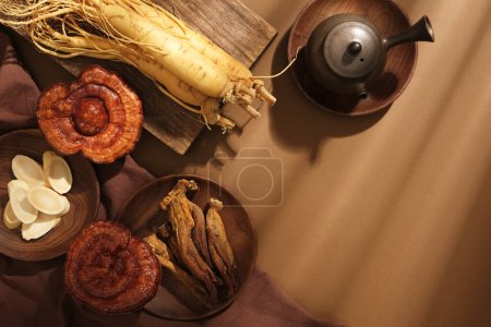 Foto de Sobre un fondo marrón, raíces frescas de ginseng, champiñones lingzhi y ginseng rojo exhibidos en bandeja de madera y decorados con tetera. Espacio en blanco para el producto de presentación y el diseño - Imagen libre de derechos