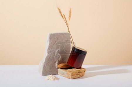 Photo for Front view of a brown cosmetic jar is placed on a stone platform, next to whole grain rice. Rice bran powder contains 10% phytic acid, which has a mild exfoliating effect. - Royalty Free Image
