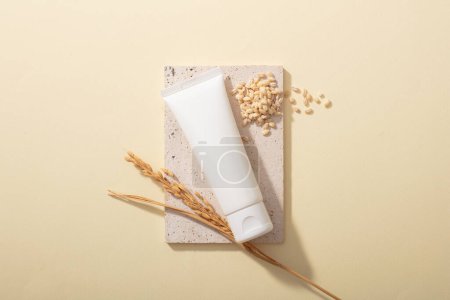 Photo for An unlabeled cosmetic tube is displayed on a podium with whole grain rice on a beige background. Mockup for cosmetic advertising with natural ingredients. - Royalty Free Image