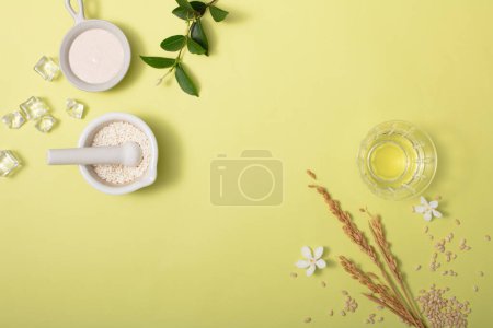 Photo for Rice bran powder is stored in ceramic utensils, ices, green leaves, a glass of water and camellia flowers are displayed on a minimalist background. Display products with ideal space. - Royalty Free Image