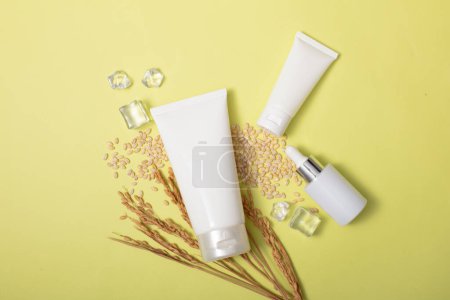 Photo for A set of unbranded cosmetics including: cleanser, cream and serum displayed on a background of ice and whole grain rice. Rice bran helps clean and brighten the skin. - Royalty Free Image
