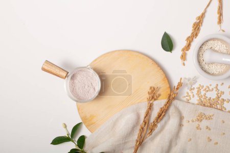 Photo for Whole rice, rice bran powder and props are arranged on a white background. Rice Bran powder contains 10% phytic acid, which gently exfoliates the skin and controls skin pigmentation. - Royalty Free Image