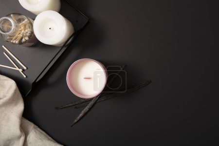 Photo for Two white candles and a bottle of cotton swabs are displayed on a black tray. A jar of scented candles is placed on the table with a black background. Candle advertisement with minimalist background. - Royalty Free Image