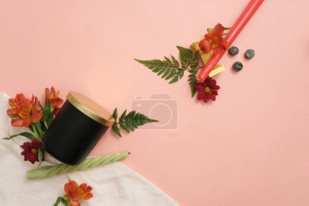 Téléchargez les photos : Bougies, fleurs fraîches, cannelle et feuilles vertes sont artistiquement décorées sur un fond rose avec du tissu blanc. Soyez créatif avec des bougies colorées. Vue du dessus. - en image libre de droit