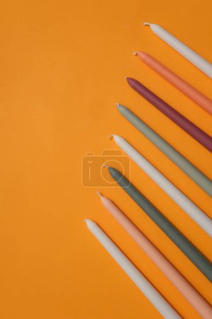 Photo for Straight candles of different colors are arranged evenly on the right side of the frame on a yellow background. Blank space for design and display. - Royalty Free Image