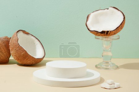 Photo for The white podium in the middle of the frame displays products with fresh coconuts decorated. Creative and sophisticated space. Cosmetics with fresh coconut extract. - Royalty Free Image