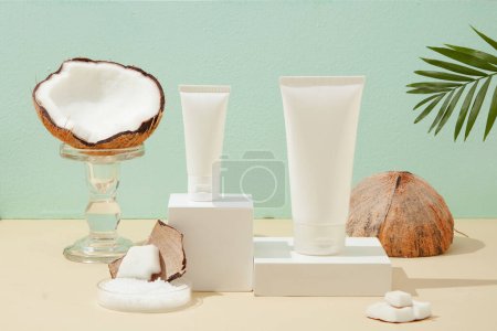 Photo for Two cosmetic tubes of two different sizes are placed on two white platforms. Half a fresh coconut is displayed on a transparent glass stand. Skin care with natural ingredients. - Royalty Free Image