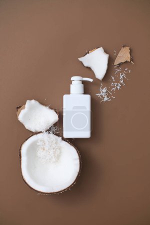 Photo for Unlabeled fresh coconut hand sanitizer bottle placed on a brown background with coconut. Coconut extract is an ingredient in many products with fragrance, moisturizing and more. - Royalty Free Image