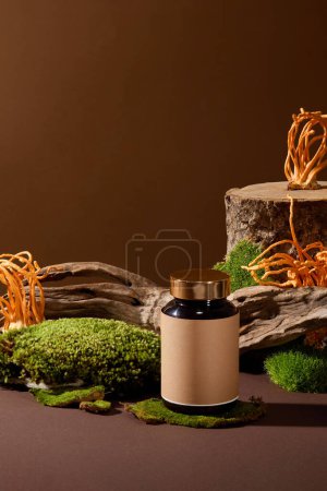 Photo for Front view of a bottle of unbranded dietary supplements placed on green moss, surrounded by logs and cordyceps. Mockup for medicine advertising. - Royalty Free Image