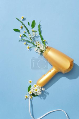 Photo for The yellow hair dryer is decorated with fresh daisies and green leaves on a pastel background. Creative images for advertising or other purposes. Top view. - Royalty Free Image