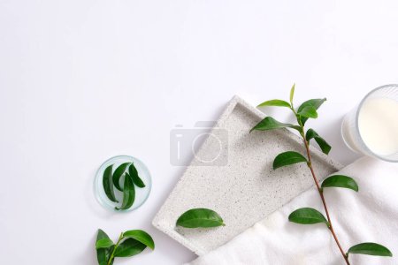 Photo for Fresh green tea leaves placed in a petri dish, a glass of white liquid on a minimalist background. Green tea is a natural ingredient that effectively prevents hair loss. - Royalty Free Image