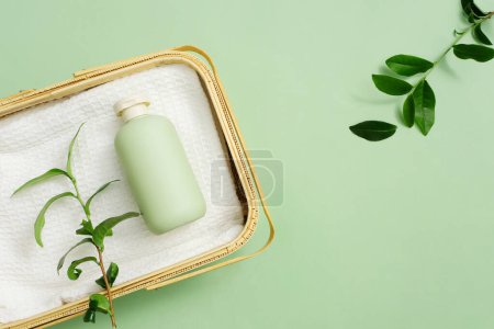Photo for Rattan basket holds towels and unlabeled shower gel bottles on a pastel green background. Green tea extract in shower gel helps brighten skin and improve back acne. - Royalty Free Image