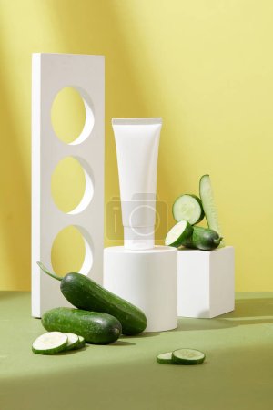 Photo for Labelless cosmetic tube is displayed on a minimalist background with some decorative props and fresh cucumbers. Cosmetics with antioxidant-rich cucumber extract. - Royalty Free Image