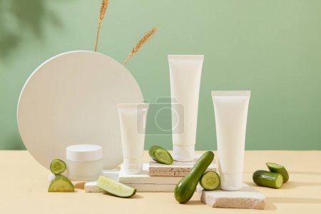 Photo for Unlabeled white plastic tubes are placed on white platforms. Cucumbers are decorated. Background with shadow. Concept of organic cosmetics. - Royalty Free Image