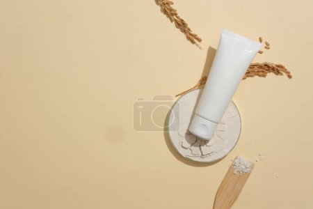 Photo for A labelless cosmetic tube stands out against a minimalist beige background. Building a vegan cosmetics brand with main ingredients from rice bran. Copy space. - Royalty Free Image