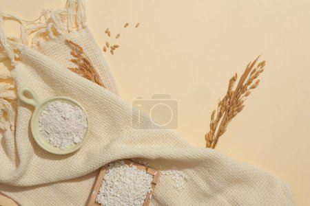 Photo for White rice is stored in a wooden tray and ceramic dish on a beige background. Rice bran is an essential oil extracted from rice bran and germ, the most nutritious components of rice grains. - Royalty Free Image