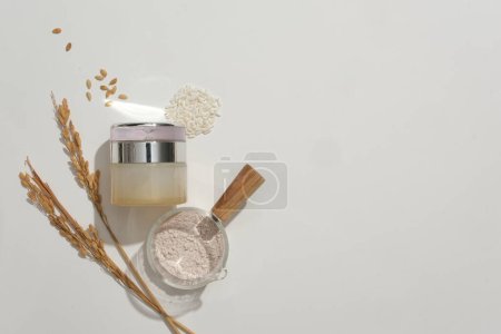 Photo for Elegantly designed cosmetic jar showcased on a white background with rice bran powder and whole rice. Blank labels offer space for creative branding and advertising. - Royalty Free Image