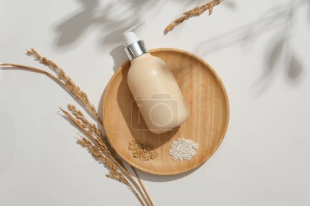 Photo for A bottle of unbranded shower gel and white rice are displayed on a round wooden tray. Minimalist white background suitable for advertising. Vegan cosmetic concept. - Royalty Free Image