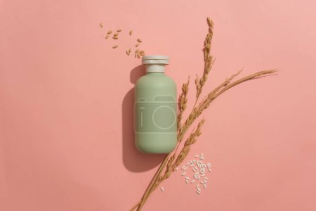 Photo for An unlabeled cosmetic bottle and rice are displayed on a pink background. Blank space for design. Cosmetic mockup with natural ingredients. Advertising space. - Royalty Free Image