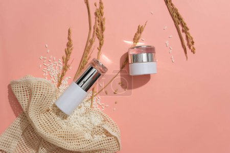 Photo for Natural cosmetics set with luxurious design on pink background. Rice is spread on the table. Mockup for cosmetic advertising. Exquisite space with top view. - Royalty Free Image
