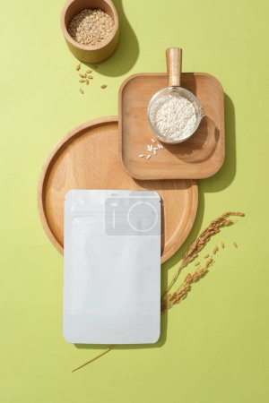 Photo for A white mask sheet, wooden tray, rice bran and rice flour are arranged on the background. The prominent ingredient in rice bran is Tocotrienol which helps prevent the aging process. - Royalty Free Image
