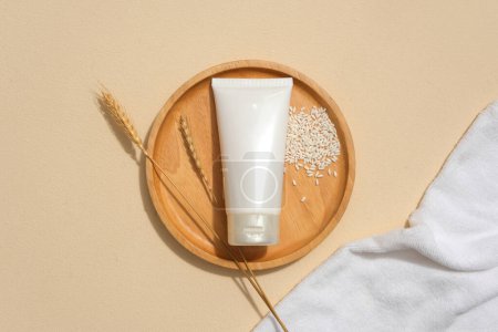 Photo for Flat lay of a tube of facial cleanser displayed on a round wooden plate with whole grain rice. Blank labels for branding and advertising. Minimalist background. - Royalty Free Image