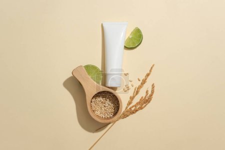 Photo for A white cosmetic tube, rice bran and fresh lemon on a minimalist background. Gamma-oryzanol in rice bran has the ability to lighten the skin by inhibiting melanin activity in the skin epidermis. - Royalty Free Image