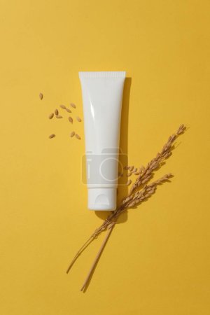 Photo for Top view of a unlabeled tube in white color decorated over yellow background with wheat seeds. Natural cosmetic concept. Empty label for branding mockup - Royalty Free Image