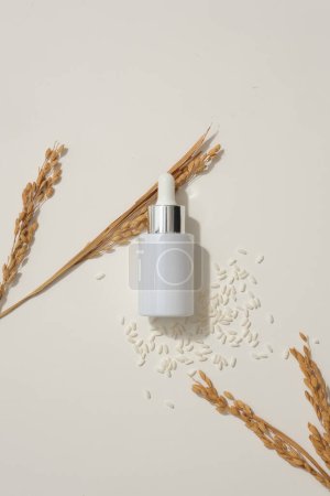 Photo for Glass bottle with dropper arranged over white background with rice and wheat ears. Mockup design. Rice water is known to help reduce skin irritation - Royalty Free Image