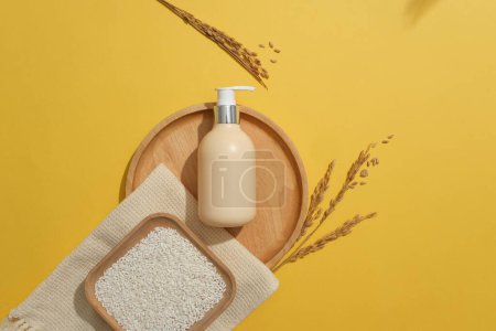 Photo for Square dish of rice placed on a scarf. Blank label pump bottle displayed on a wooden tray on yellow background. Container packaging of skin care branding - Royalty Free Image