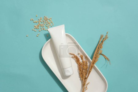 Photo for Cosmetic tube without label decorated with wheat ears on a dish. A handful of wheat seeds featured. Empty label tube for natural beauty product advertising - Royalty Free Image