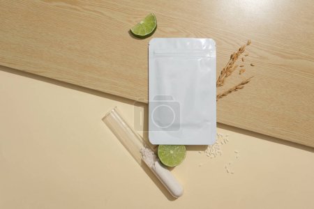 Photo for Unbranded mask package placed on wooden surface, displayed with slices of lime. Rice bran powder contained inside a test tube. Skin care product concept - Royalty Free Image