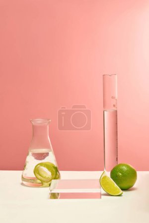 Photo for An Erlenmeyer Flask, a test tube, a glass podium and lemons are displayed on a pink background. Research and develop cosmetics from lemon extract. Copy space. - Royalty Free Image