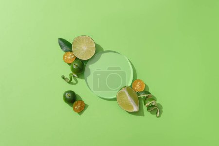 Téléchargez les photos : Sur fond vert, un podium en verre transparent est entouré de citrons frais et de kumquats un espace d'exposition invitant pour mettre en valeur les produits naturels. - en image libre de droit
