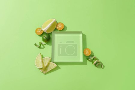 Foto de Un podio de cristal transparente se coloca sobre un fondo verde, rodeado de limones frescos y kumquats. Podio vacío para mostrar productos naturales. - Imagen libre de derechos