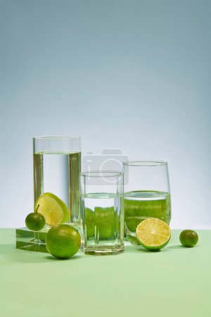Photo for Transparent glasses of water and fresh lemons are placed on the table with a light blue background. Fresh space with fresh lemon rich in vitamin C. Copy space for ads. - Royalty Free Image