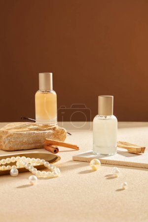 Photo for Front view of glass spray bottle unlabeled decorated on brown background with pearl necklace, cinnamon sticks and vanilla. Mockup scene for advertising perfume product - Royalty Free Image