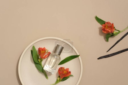 Foto de Vista superior de flores frescas y hojas verdes decoradas con varillas de vainilla sobre fondo beige. Un recipiente redondo botella de perfume de vidrio sin etiqueta para el diseño - Imagen libre de derechos